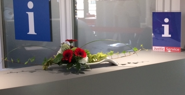 Infotresen vom Eingangsbereich des Justizzentrums Göttingen mit einem Blumengesteck